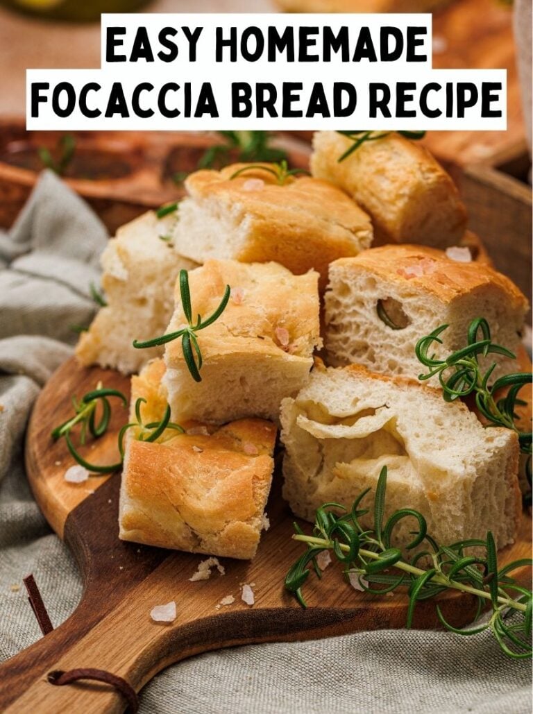 Slices of rosemary and sea salt focaccia bread stacked on a wooden serving board with fresh rosemary sprigs.