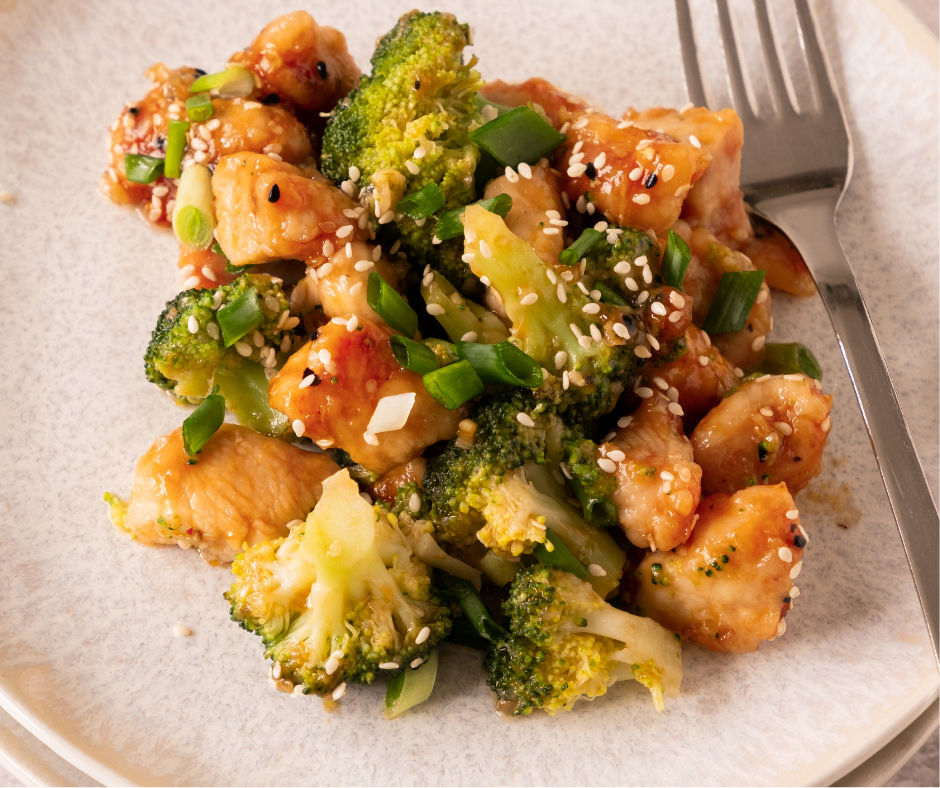 Honey garlic chicken and broccoli in a black wok next to a plated serving.