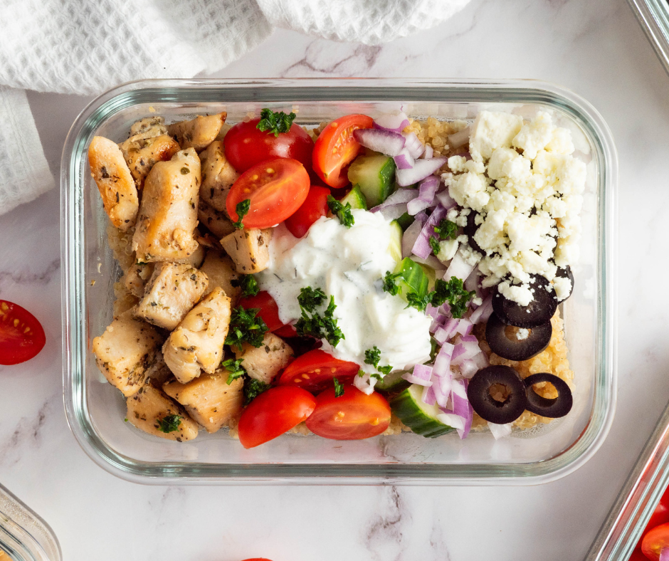 Overhead view of a Greek Mediterranean quinoa bowl recipe in a glass airtight container.