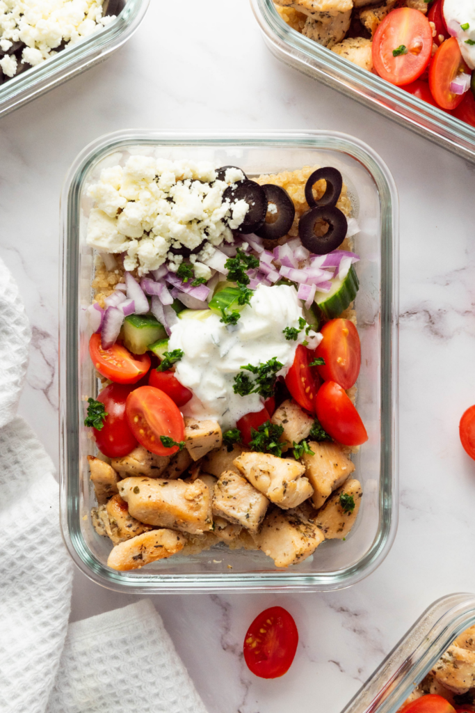 Close-up of a healthy quinoa bowl with Mediterranean toppings and creamy Greek yogurt sauce.