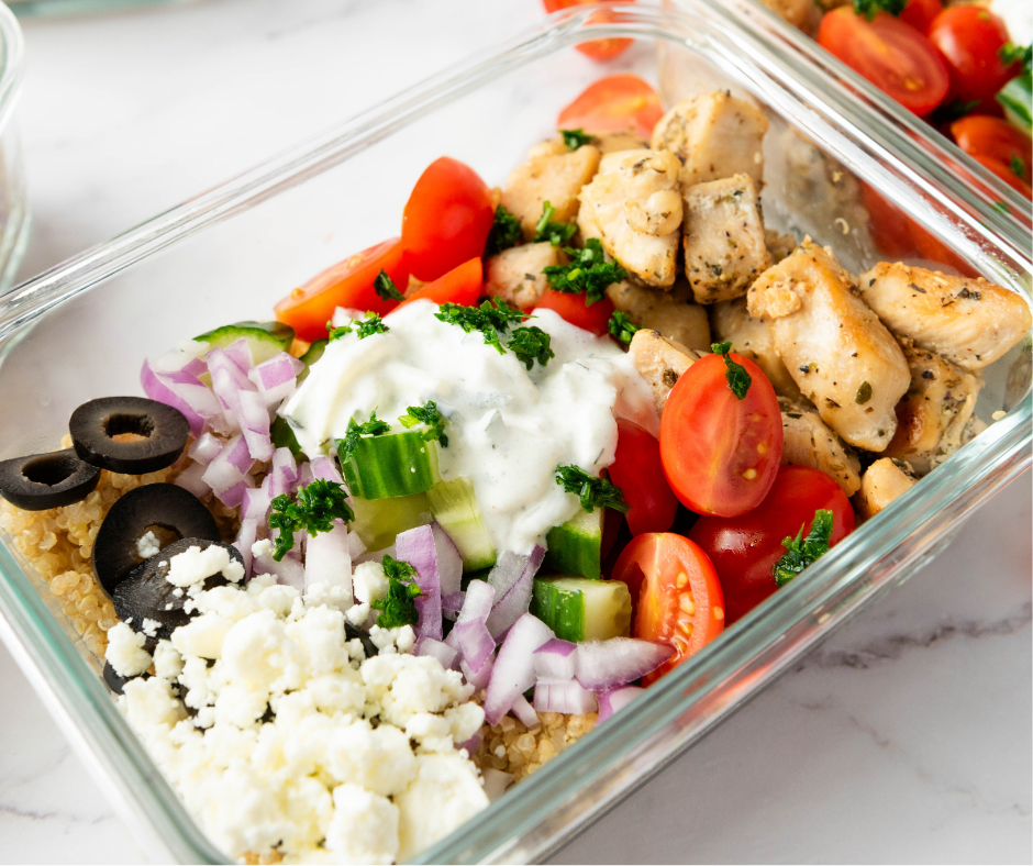 etail shot of Greek chicken quinoa bowl ingredients like Kalamata olives, feta cheese, and seasoned chicken.