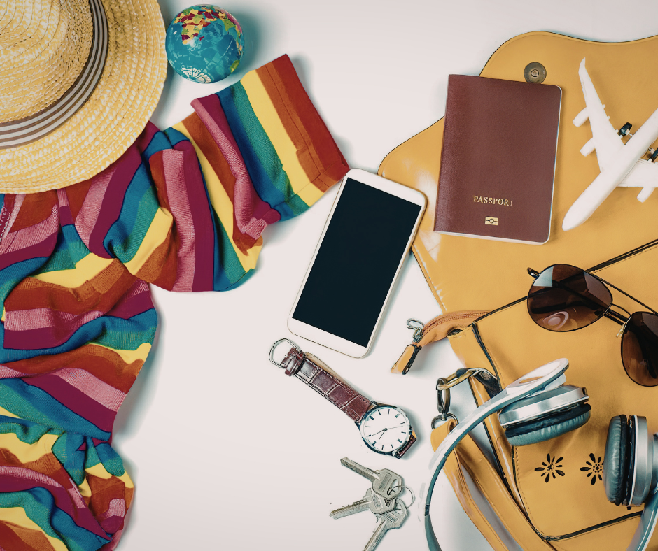 Overhead view of travel essentials including a passport, smartphone, sunglasses, and a sun hat.