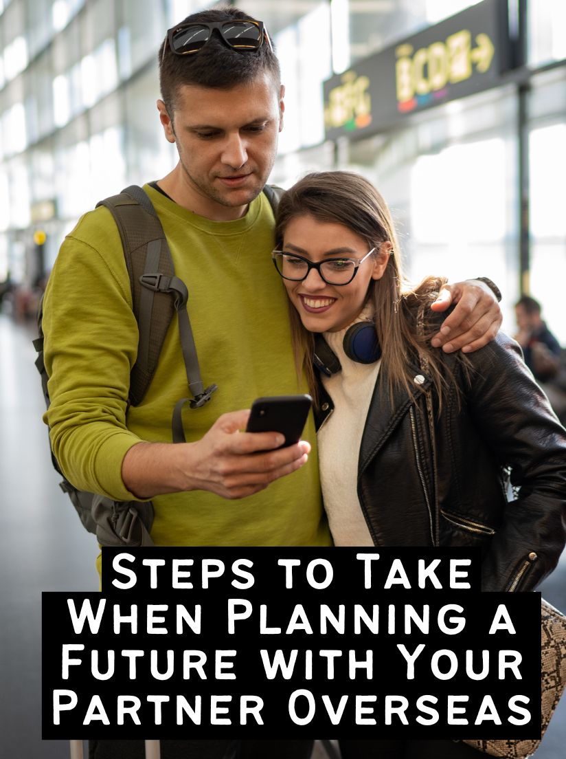 A young couple standing in a bright airport terminal, smiling while looking at a smartphone together, representing the planning phase of travel.