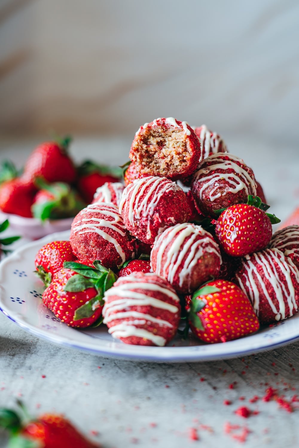 A close-up of a stacked strawberry energy bite with a bite taken out, showing the soft, chewy oat and cashew center.