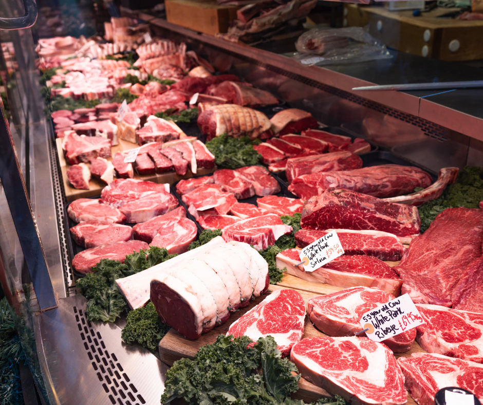A well-stocked butcher’s counter featuring various cuts of beef, including ribeye and sirloin, with handwritten price tags.
