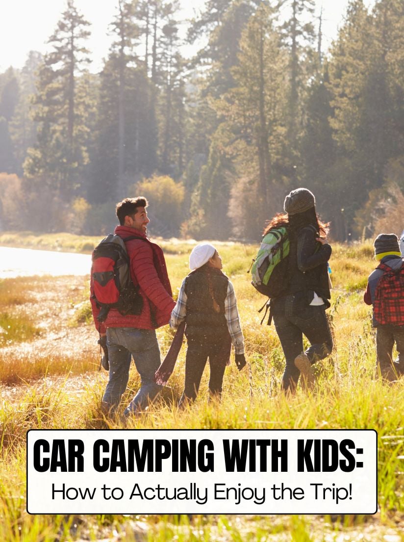A family of four with backpacks walking through tall grass toward a lake during a sunny autumn car camping trip.