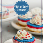 Fluffy whipped cream swirls on top of a red, white, and blue layered mini cheesecake dessert, showcasing a smooth and creamy texture.