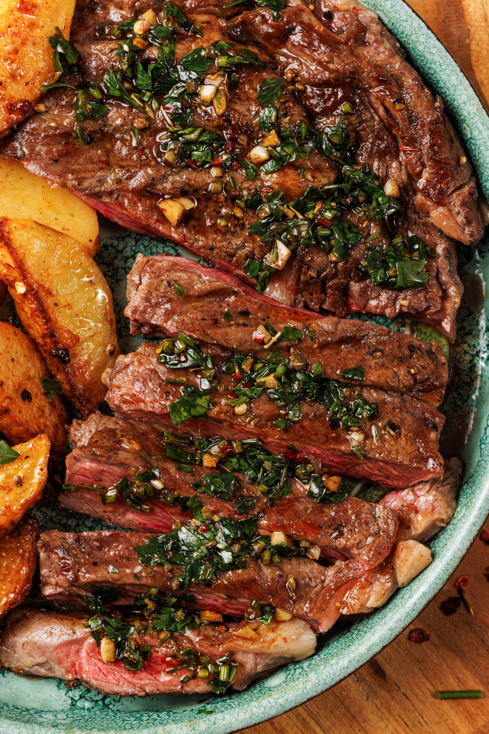 Close-up of sliced steak strips topped with a zingy sauce made of parsley, olive oil, and red wine vinegar.