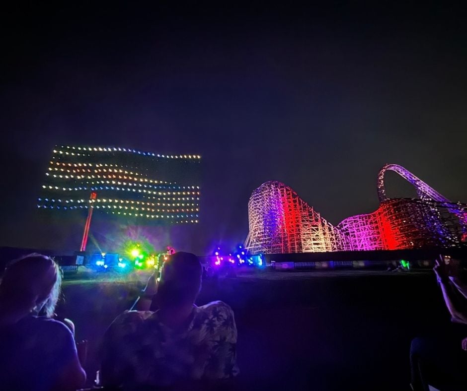 A drone light show in the night sky forming the American flag above the Iron Gwazi roller coaster at Busch Gardens Tampa Bay.