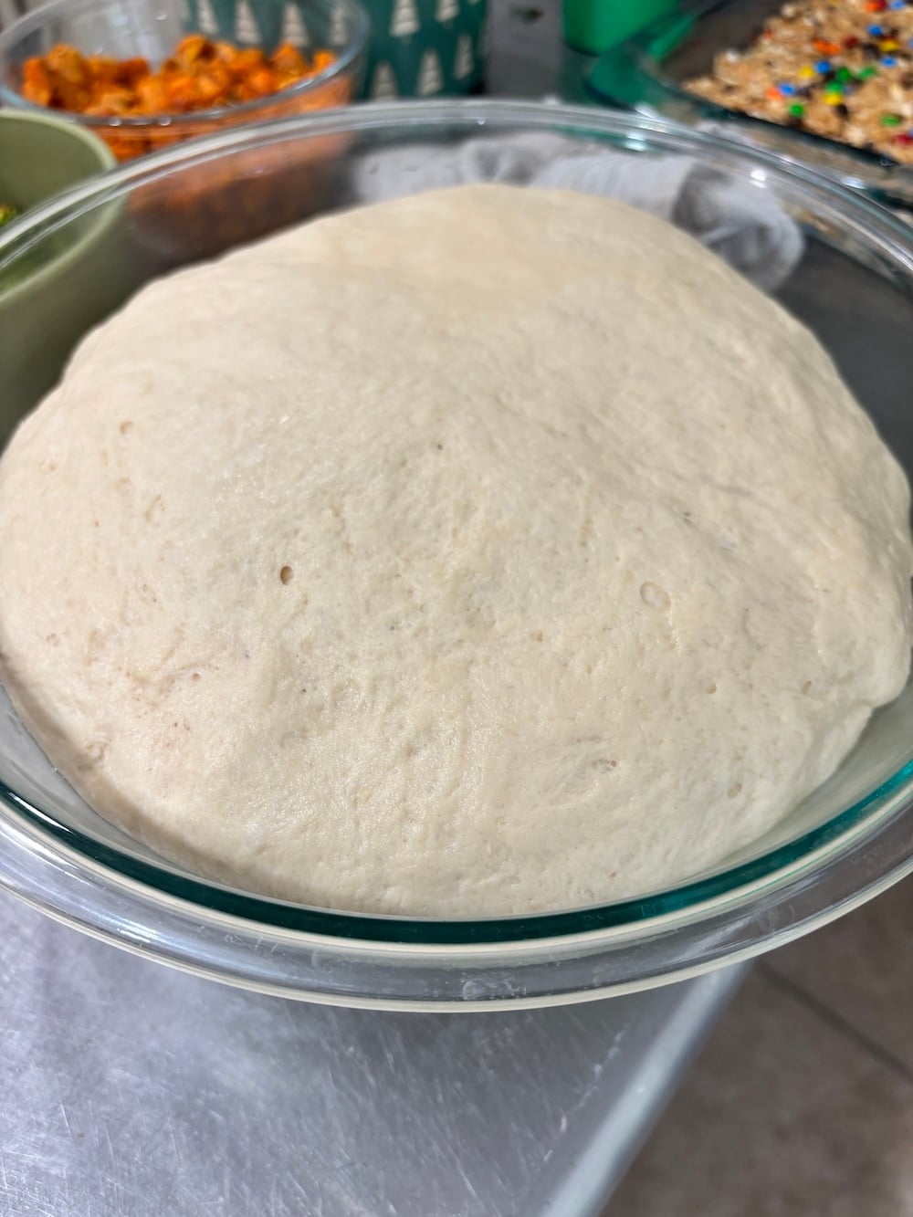 White bread dough in a glass bowl after the first rise, expanded to double its size.