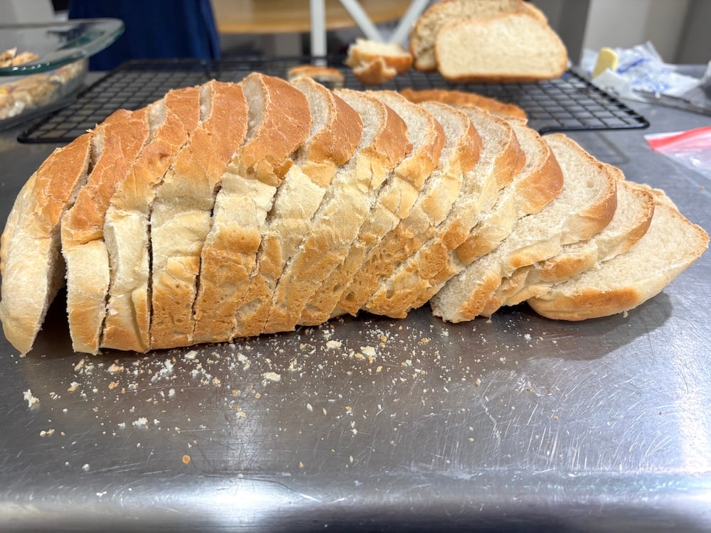 Even slices of homemade white bread fanned out on parchment paper.