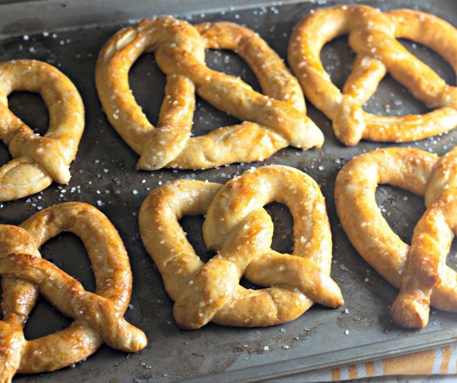 Homemade soft pretzels on a baking sheet.