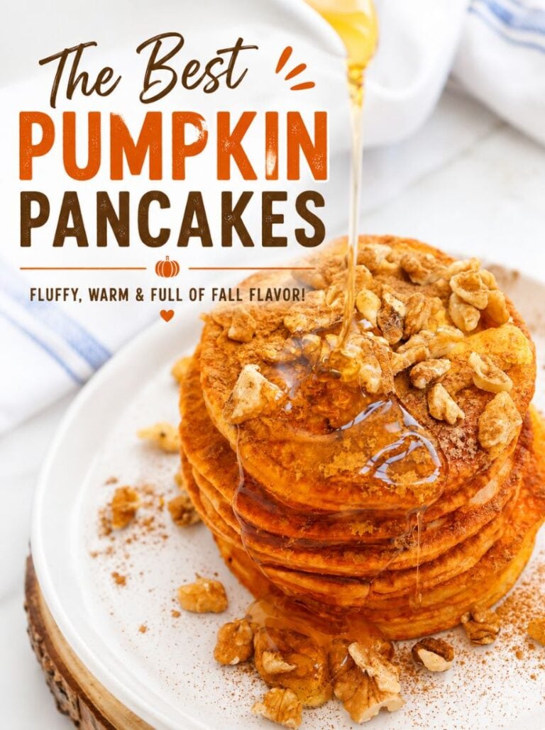 A stack of five pumpkin spice pancakes on a white plate, topped with chopped walnuts and drizzled with maple syrup. The background is a rustic wooden table with a napkin and other breakfast items, out of focus.