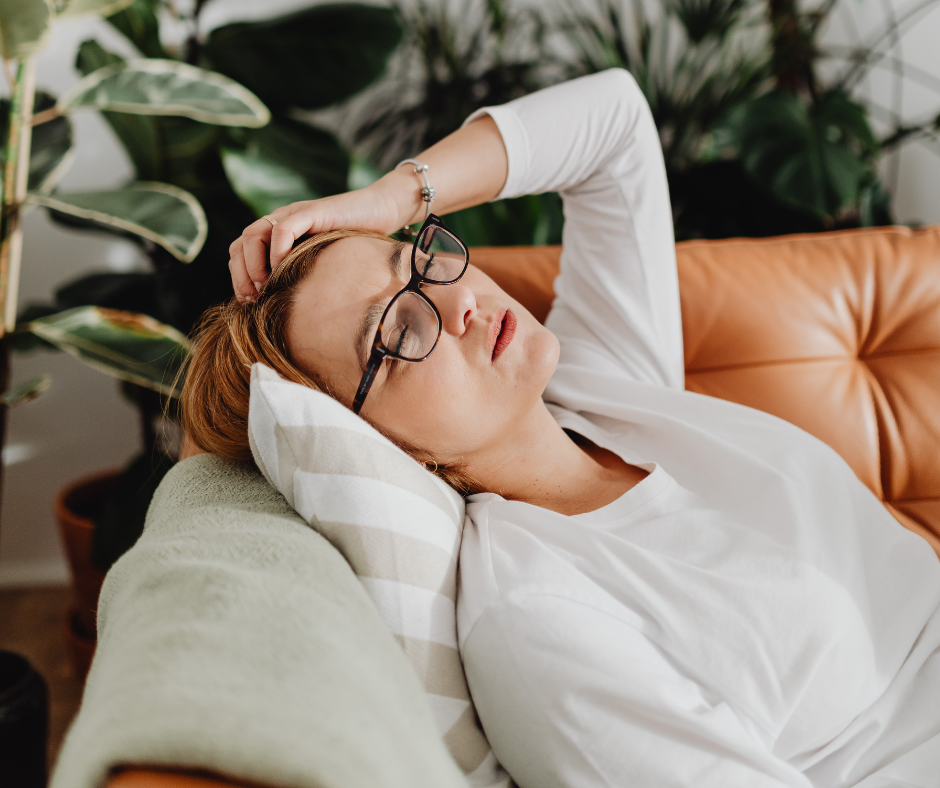Woman resting on a couch with eyes closed after a red-eye flight, showing the exhaustion and fatigue many travelers experience after overnight travel.