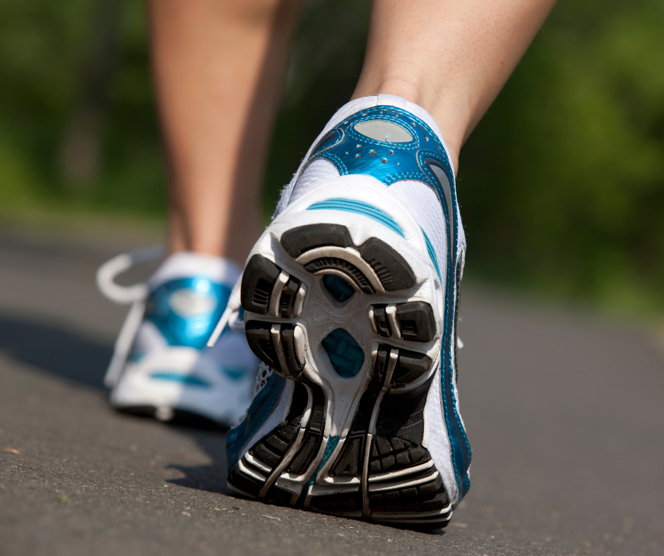 Close-up of a person walking outdoors in running shoes, illustrating how light exercise can help you recover after a red-eye flight.